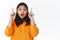 Close-up portrait attractive curious asian girl pointing fingers up, telling you big news, show awesome discounts shop