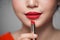 Close up portrait of attractive girl holding red lipstick over g