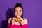 Close-up portrait of attractive hungry cheerful girl eating hot burger thinking copy space isolated over bright violet