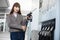 Close up portrait of attractive smiling young Caucasian woman, holding refueling petrol nozzle and posing to camera at