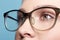 Close-up portrait of attractive young woman in glasses on blue background