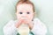 Close up portrait of a baby girl with a milk bottle lying on a green knitted blanket