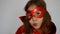 Close up portrait baby girl plays superhero. Funny child in a red raincoat and mask playing power super hero. Superhero