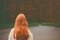 close-up portrait back view of a young red-haired woman in a forest with the background out of focus, IA generative