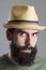 Close up portrait of bearded man wearing straw hat with intense look at camera.