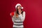 Close up portrait beautifiul caucasian woman in red Santa hat on red studio background. Christmas and New Year holiday concept