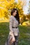 Close up portrait of a beautiful brunette girl with make up and in elegant fall outfit, posing in the park.