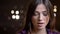 Close-up portrait of beautiful caucasian brunette girl watching downwards with contempt on blurred lights background.