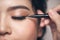 Close-up portrait of beautiful girl touching black eyeliner to h