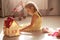 Close up portrait of beautiful toddler girl with pigtails sitting on floor playing with toy doll house, toy baby carriage near