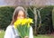 Close up portrait of beautiful tween romantic girl holding bouquet of bright yellow spring daffodil flowers at her face smelling i