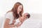 Close up portrait of beautiful young asian mother with newborn baby. Side view of a young woman playing with her little baby in