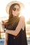 Close-up portrait of a beautiful young girl with long dark hair wearing straw hat, dark sunglasses. She plays with her