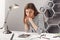 Close up portrait of beautiful young serious female architect student with brown hair in striped look, holding head with