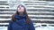 Close-up portrait of beautiful young smiling caucasian woman in winter jacket, hat and scarf. Brunette girl snowy wood