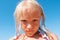 Close up portrait of blond preschool girl looking down to the camera on sunny day outdoors.