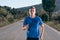 Close up portrait of a blonde, sweaty male runner athlete. Running on an empty road in the woods