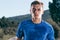 Close up portrait of a blonde, sweaty male runner athlete. Running on an empty road in the woods