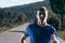 Close up portrait of a blonde, sweaty male runner athlete. Running on an empty road in the woods