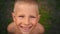 Close-up portrait of a blue-eyed little boy looking and smiling directly at the camera, a piercing look of a 6-year-old