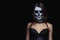Close up portrait of brown-haired woman with Halloween skull make up over black background