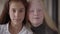 Close-up portrait of brunette girl with brown eyes and blonde girl with grey eyes looking at the camera. Concept of