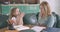 Close-up portrait of Caucasian daughter and mother doing homework together at home. Girl asking her mom to help as woman