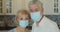 Close up portrait of Caucasian happy middle-aged adult wife and husband in medical masks on the kitchen background. and