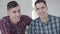 Close-up portrait of Caucasian twin brothers looking at camera and smiling. Two positive young men posing at home