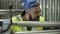 Close-up portrait of Caucasian worker with black beard looking at equipment for metal pipes production. Serious man