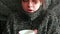 Close up portrait of Caucasian young woman with sick look, woman sneezing and basking in warm sweater and glass of hot drink. Sele