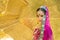 Close up portrait charming Asian woman wearing a purple Indian traditional saree with a golden wall background