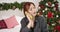 Close-up portrait of charming redhead woman talking on the phone with Christmas decorations at the background. Beautiful