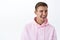 Close-up portrait of cheeky blond guy in pink hoodie, wink and laugh, smiling broadly, hinting you got like this product