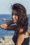 Close-up portrait of cheerful suntanned young woman over seaside background