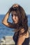 Close-up portrait of cheerful suntanned young woman over seaside background