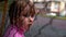 Close-up portrait of a child of a girl who stands behind a chain-link fence, her hair is short, and she directs her gaze