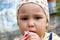 Close up portrait of a child with a piercing gaze eating a healthy vegetable. Little hungry child eating fresh ripe