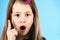 Close up portrait of a child school girl holding up point finger in I have an idea gesture isolated on blue background