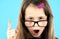 Close up portrait of a child school girl wearing looking glasses holding up point finger in I have an idea gesture isolated on
