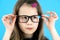 Close up portrait of a child school girl wearing looking glasses isolated on blue background