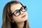 Close up portrait of a child school girl wearing looking glasses isolated on blue background