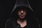 Close-up portrait of a courageous man in a deep dark hood on a black background. The concept of secrecy of secrets and