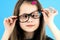 Close up portrait of a cross eyed child school girl wearing looking glasses isolated on blue background