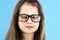 Close up portrait of a cross eyed child school girl wearing looking glasses isolated on blue background