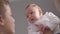 Close-up portrait curios adorable infant with mother and brother at home indoors. Happy carefree Caucasian baby girl in