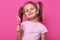 Close up portrait of cute child wearing rose casual t shirt, happy little girl holding big sugar lollipop, has gladness facial