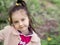 Close-up portrait of a cute girl with blue unusual eyes. baby in a light pink coat and dress, with a ponytail