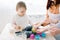 Close-up portrait of cute little baby girl sitting on the dinner table and playing with dough for baking muffins in