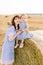 Close up portrait of cute little baby girl sitting on hay stack bale and posing to camera together with her charming